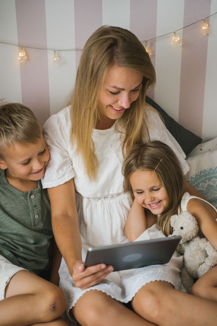 Mother and children enjoying quality time together on a tablet indoors. Joyful family scene.